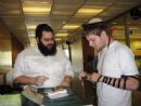 Rabbi Yochanan Rivkin helps Chabad Board member Zack Rozen put on Tefilin at the Chabad Tefilin table in the LBC